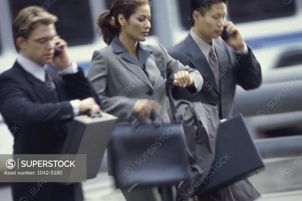 Stock Photo: 1042-5180 Two businessmen and a businesswoman walking side by side