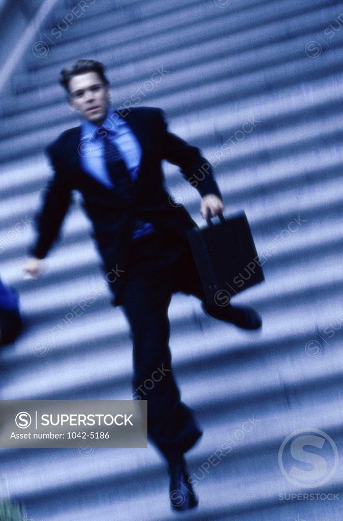 Stock Photo: 1042-5186 Businessman running down a staircase with a briefcase