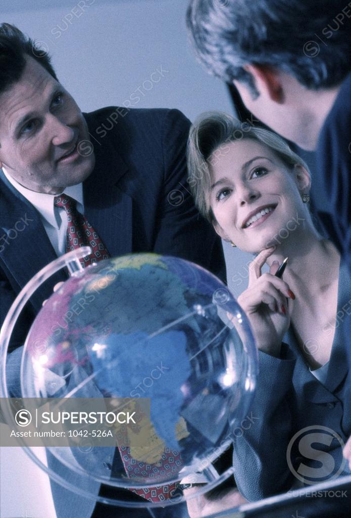 Stock Photo: 1042-526A Two businessmen and a businesswoman in front of a globe