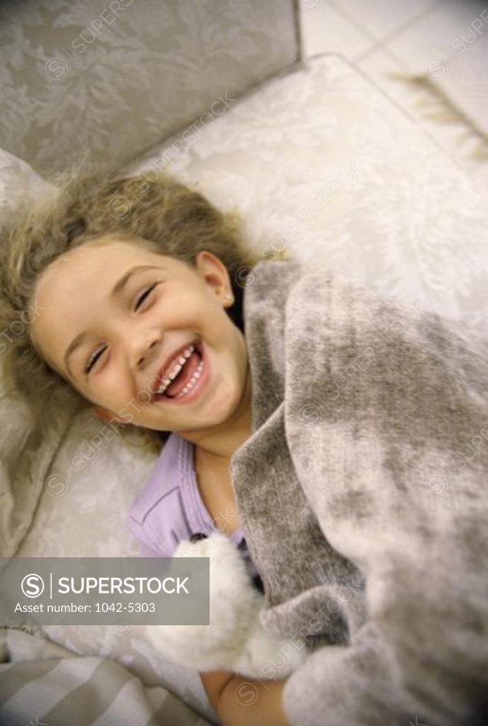 Stock Photo: 1042-5303 High angle view of a girl lying on a couch laughing