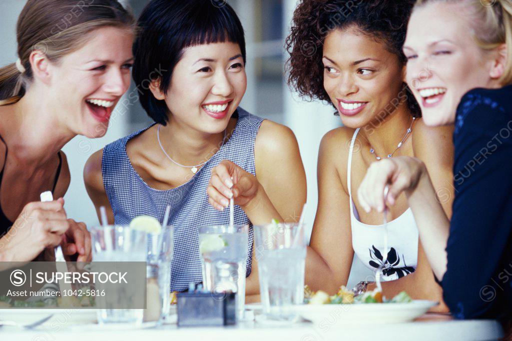 Stock Photo: 1042-5816 Four young women sitting at a dining table in a restaurant