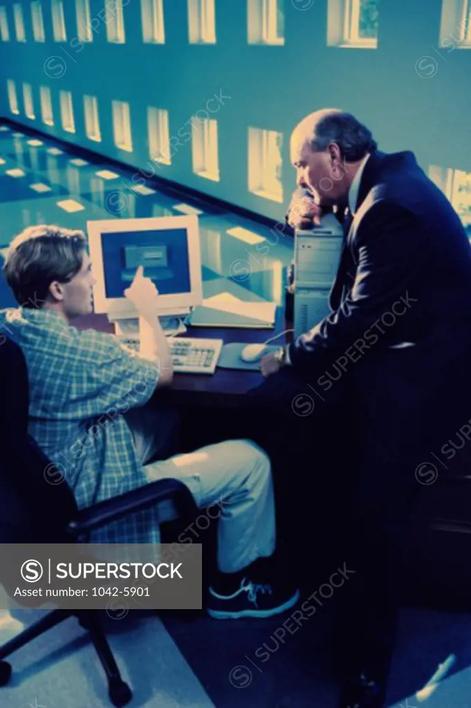Two businessmen using a computer in an office