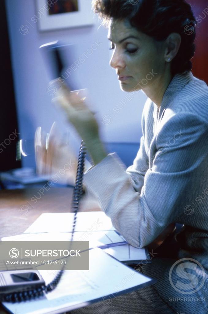 Stock Photo: 1042-6123 Side profile of a businesswoman holding a telephone receiver