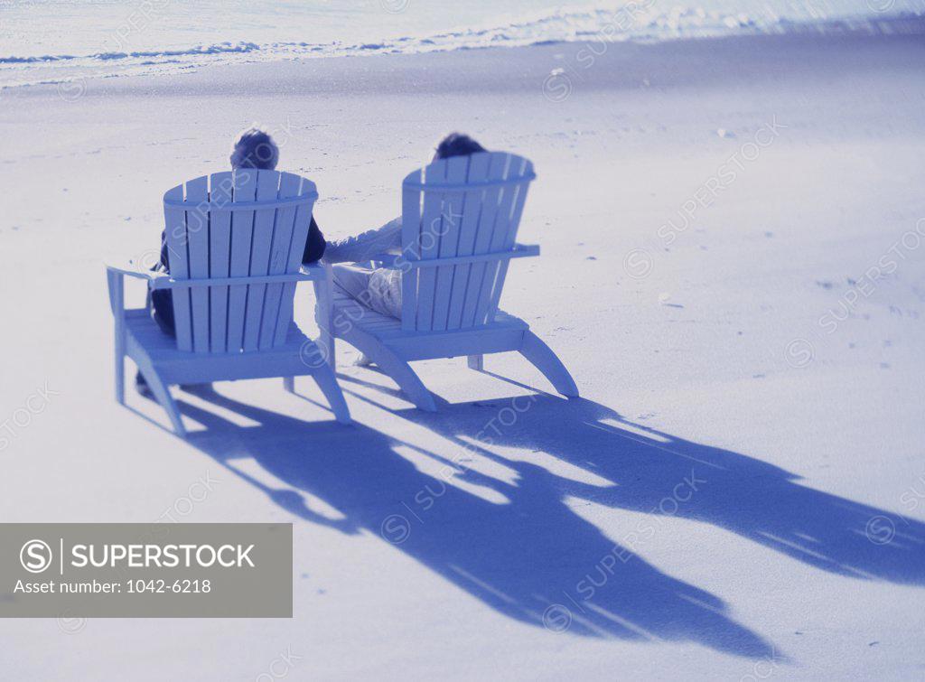 Stock Photo: 1042-6218 Senior couple sitting on deck chairs on the beach