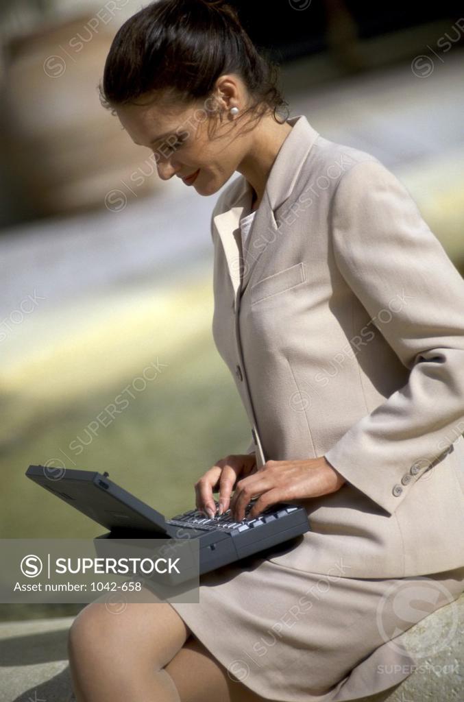 Stock Photo: 1042-658 Side profile of a businesswoman sitting using a laptop