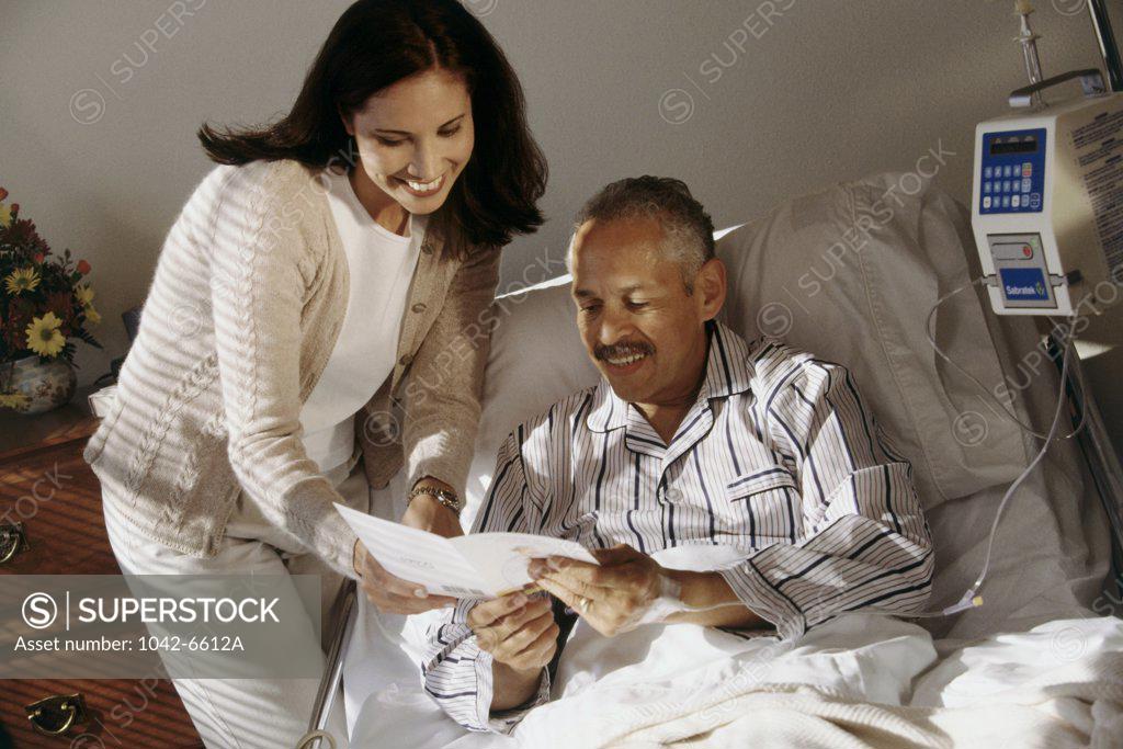 Stock Photo: 1042-6612A Senior man reading a get well card with a young woman standing near him