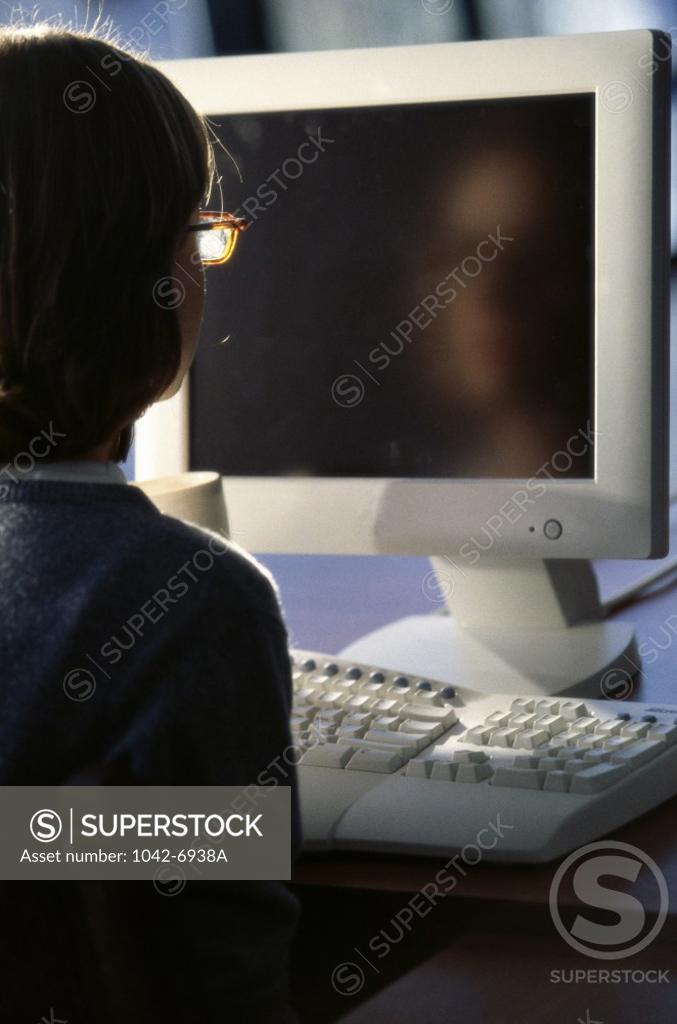 Stock Photo: 1042-6938A Rear view of a teenage girl in front of a computer monitor