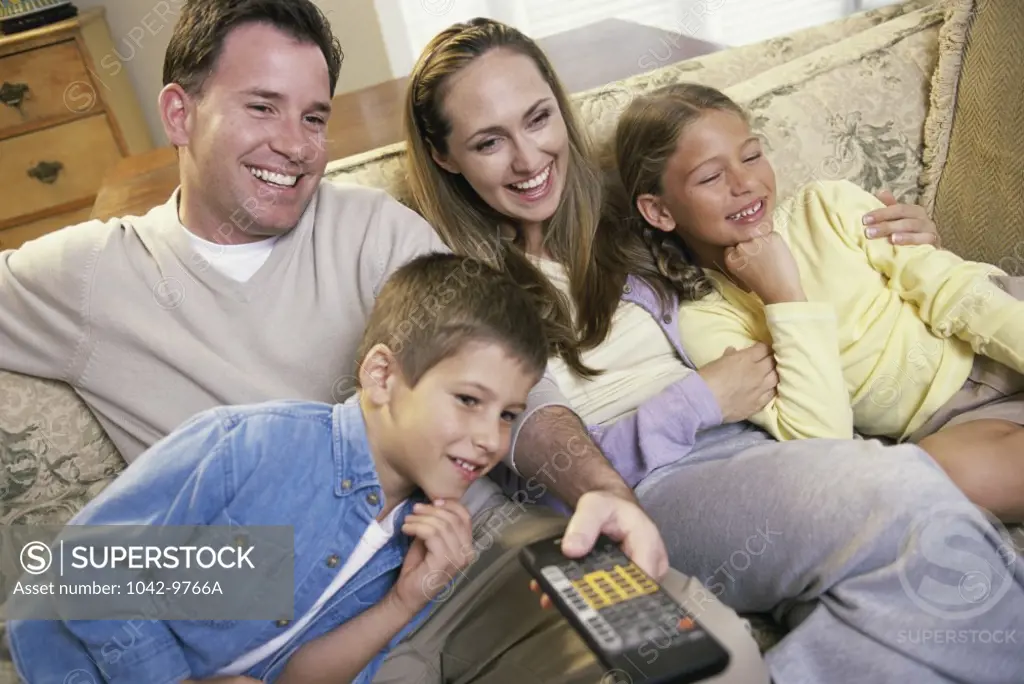 Parents watching television with their son and daughter