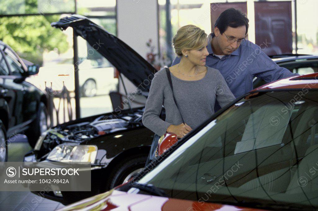 Stock Photo: 1042-9842A Mid adult couple looking at a car in a showroom