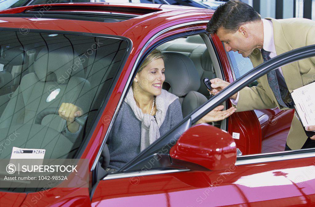 Stock Photo: 1042-9852A Mid adult woman sitting in a car talking to a salesman in a showroom