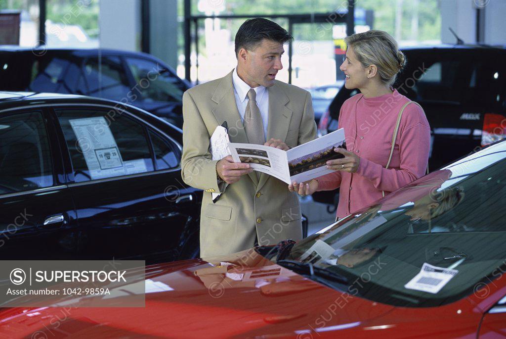 Stock Photo: 1042-9859A Car salesman showing a mid adult woman a brochure