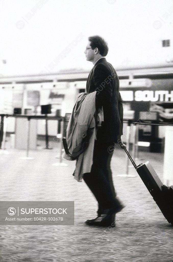 Stock Photo: 1042R-10267B Side profile of a businessman pulling a suitcase