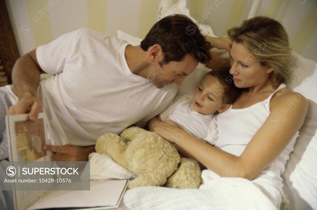 Stock Photo: 1042R-10576 Father and mother lying in bed with their son