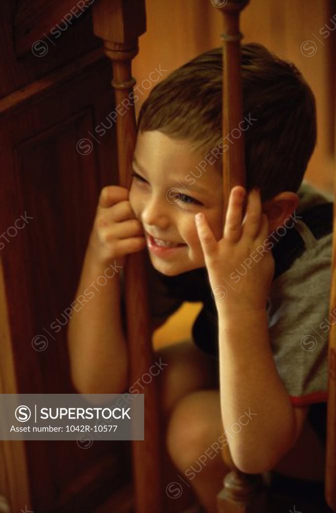 Stock Photo: 1042R-10577 Boy peeking through a wooden banister