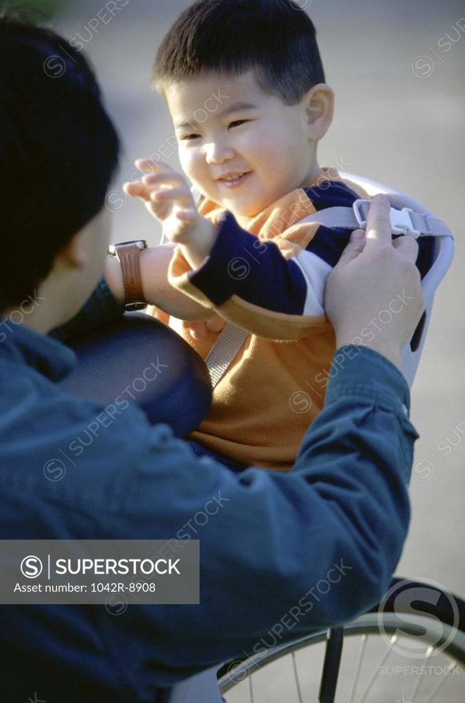 Stock Photo: 1042R-8908 Father strapping his son on a bicycle