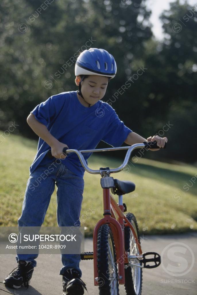Stock Photo: 1042R-8909 Boy holding a bicycle