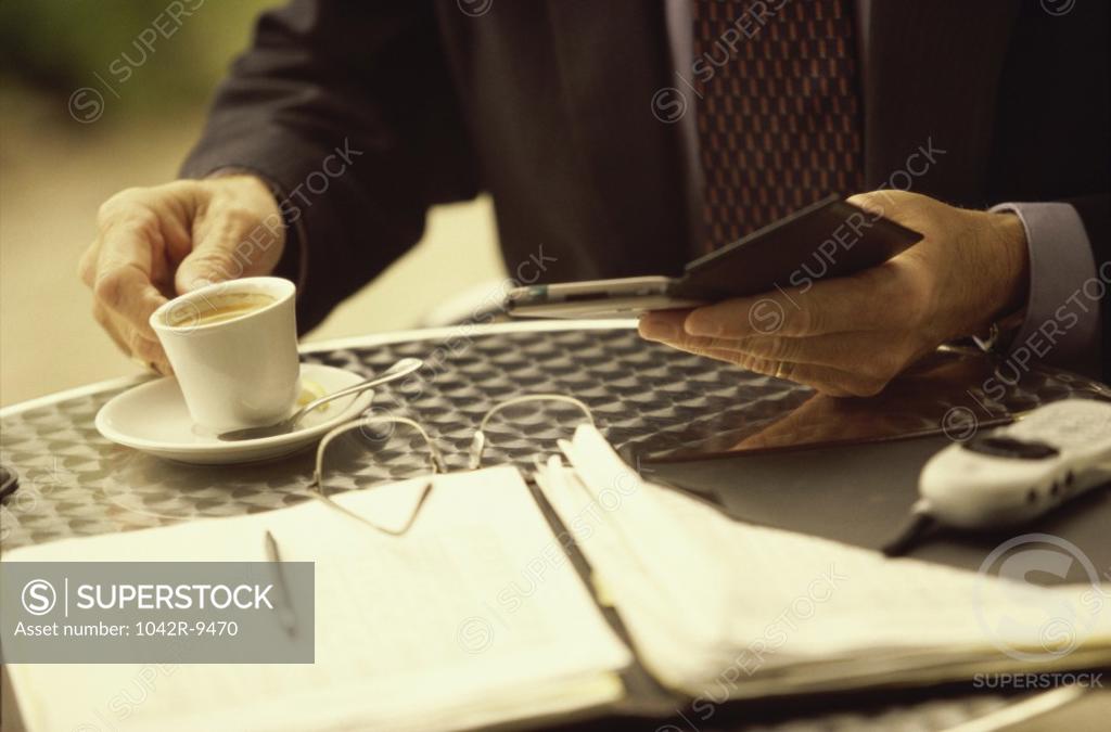Stock Photo: 1042R-9470 Businessman holding a wallet and a cup of coffee