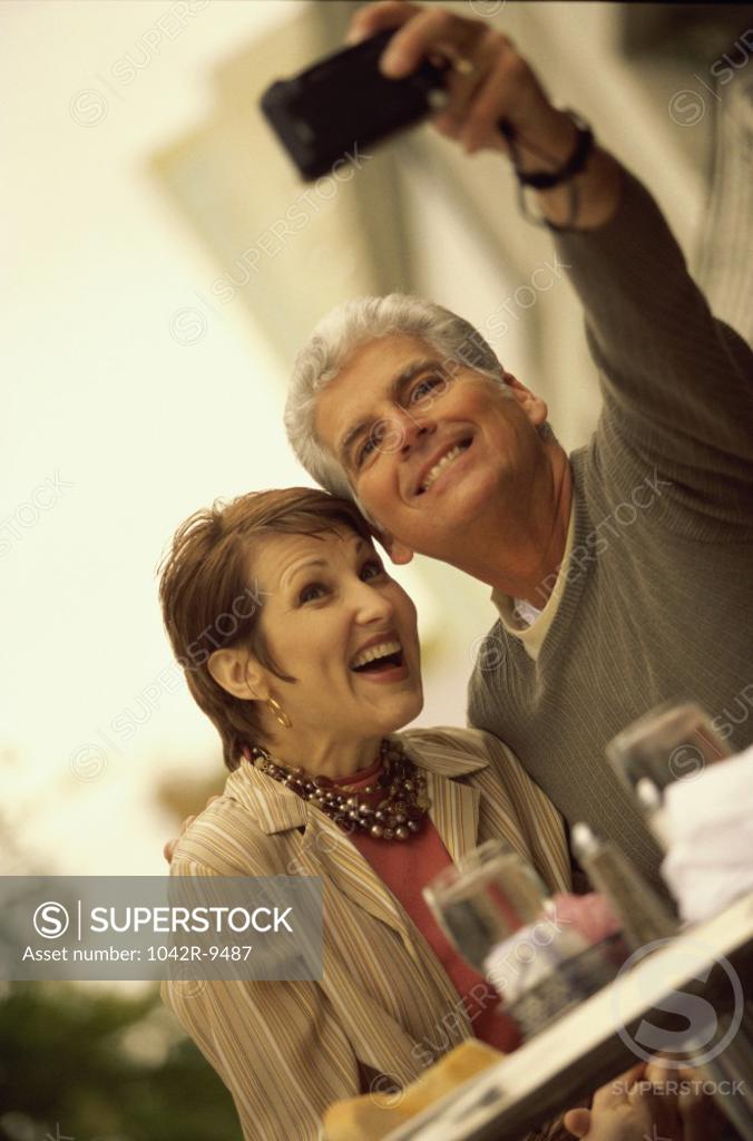 Stock Photo: 1042R-9487 Mid adult couple taking a photograph of themselves