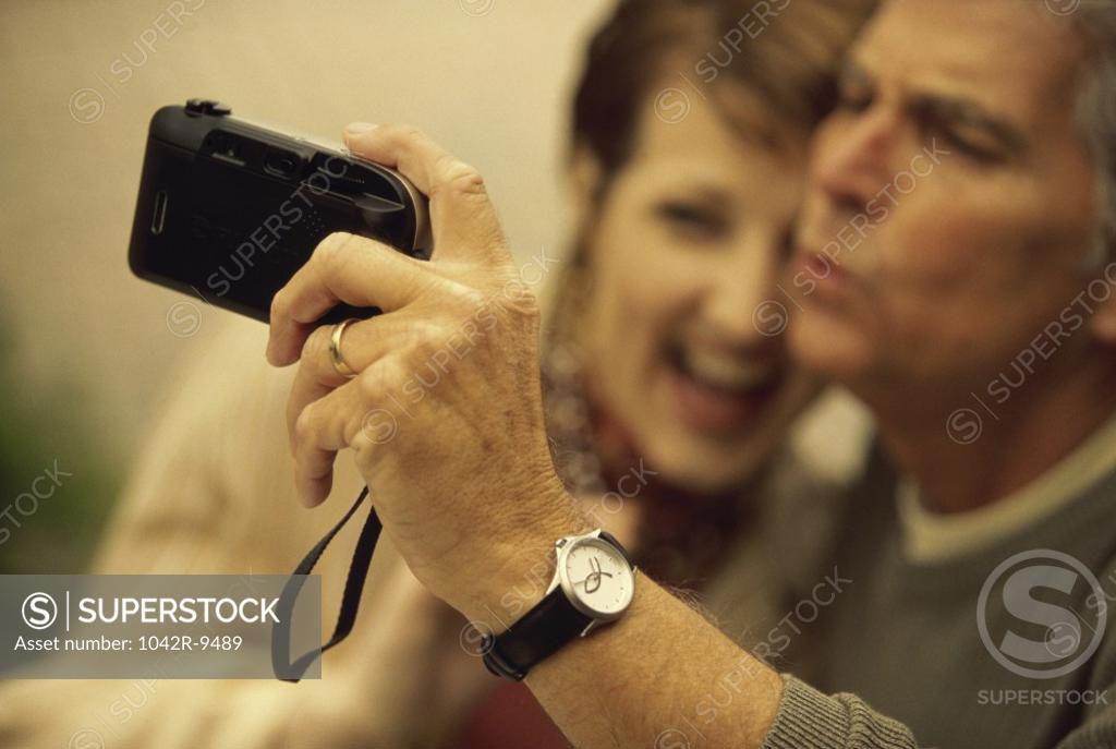 Stock Photo: 1042R-9489 Mid adult couple taking a photograph of themselves