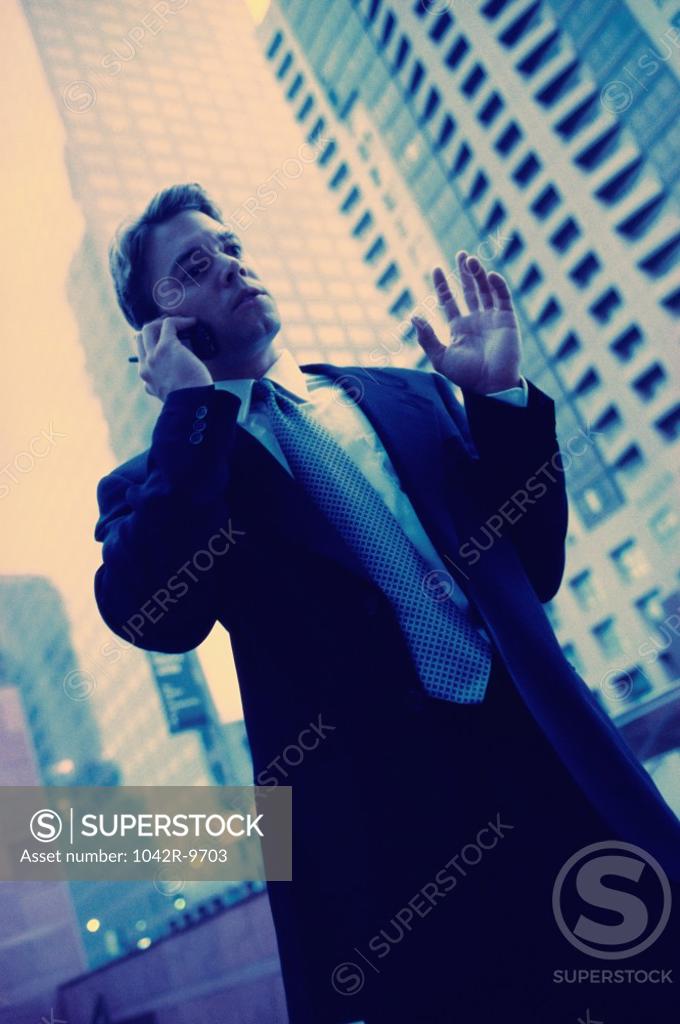 Stock Photo: 1042R-9703 Low angle view of a businessman talking on a mobile phone
