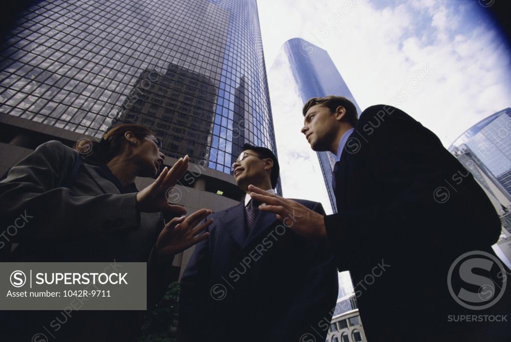 Stock Photo: 1042R-9711 Low angle view of a businesswoman and two businessmen talking
