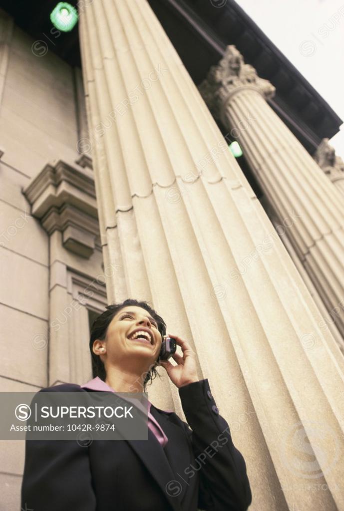 Stock Photo: 1042R-9874 Low angle view of a businesswoman talking on a mobile phone smiling