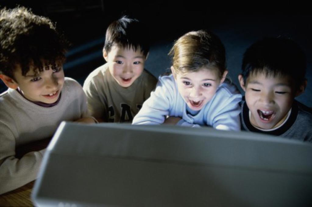 Group of boys laughing in front of a computer monitor