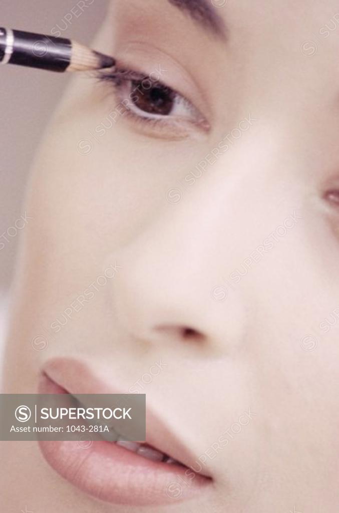 Stock Photo: 1043-281A Young woman applying eyeliner