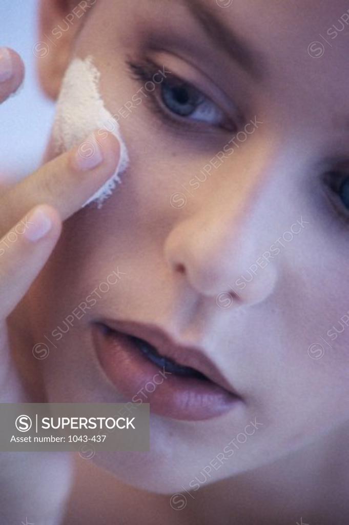 Stock Photo: 1043-437 Young woman applying lotion to her face