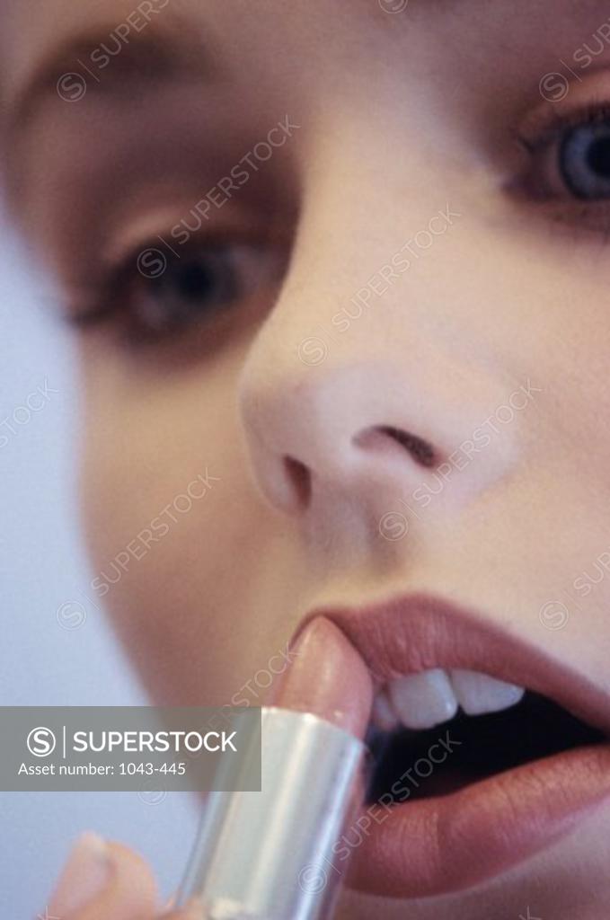 Stock Photo: 1043-445 Young woman applying lipstick