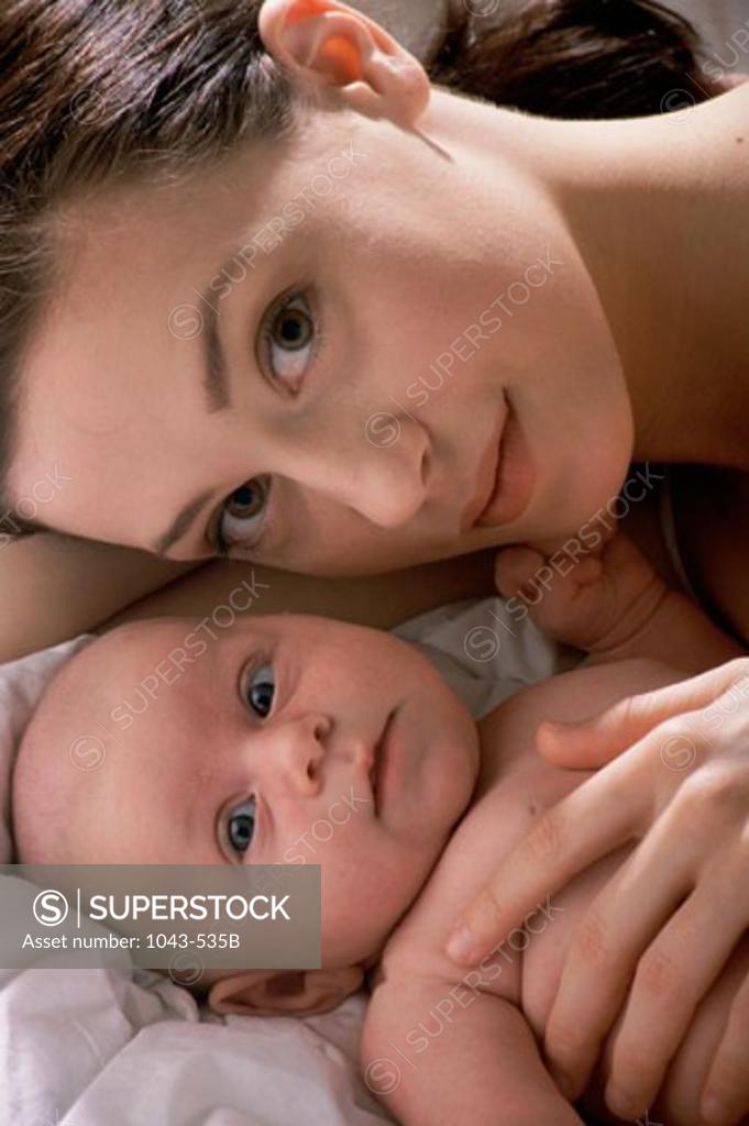 Stock Photo: 1043-535B Portrait of a mother lying on a bed with her baby boy