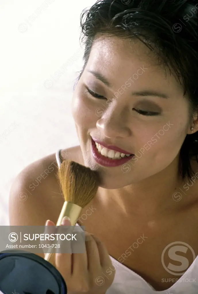 Young woman applying blush