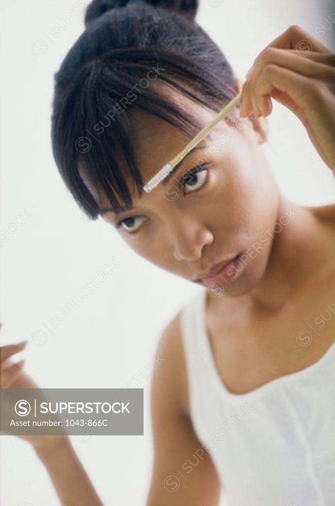 Stock Photo: 1043-866C Young woman brushing her eyebrows