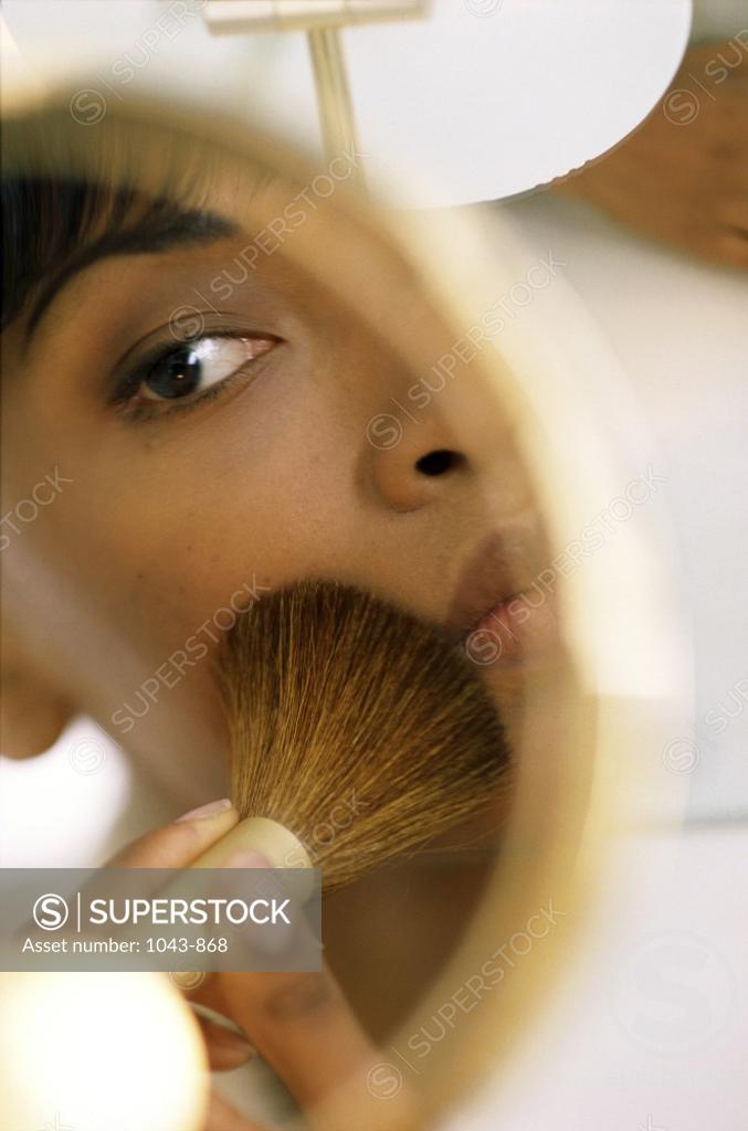 Stock Photo: 1043-868 Young woman applying make-up in a mirror