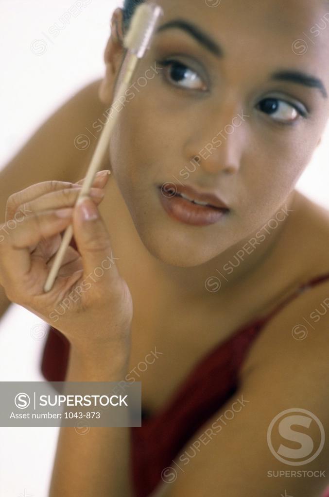 Stock Photo: 1043-873 Young woman brushing her eyebrows