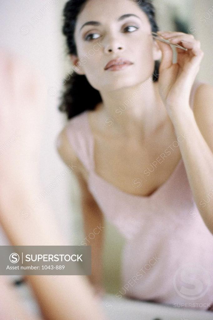 Stock Photo: 1043-889 Close-up of a young woman using a tweezers on her face