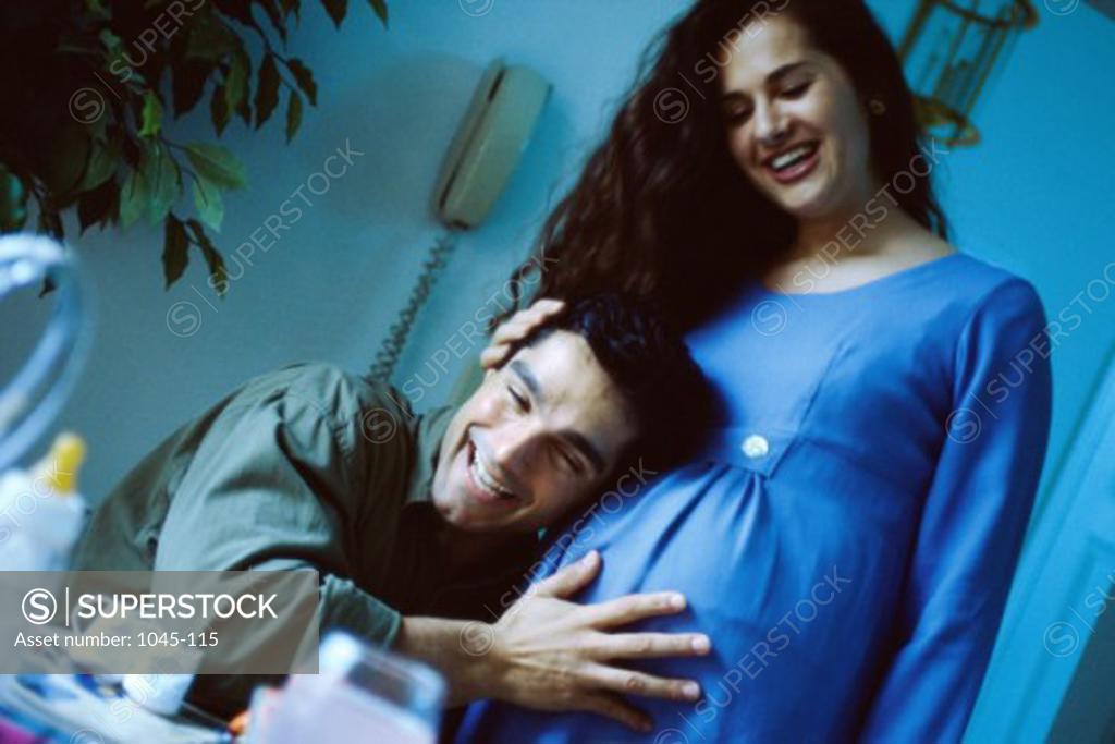 Stock Photo: 1045-115 Husband with his head against his pregnant wife's abdomen