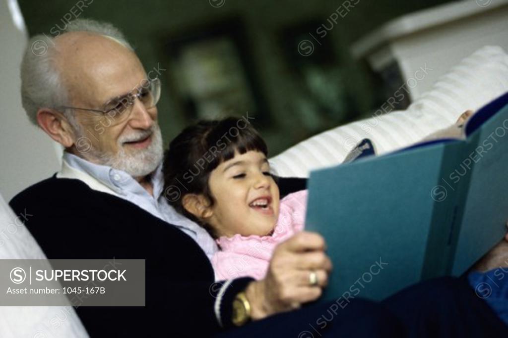 Stock Photo: 1045-167B Grandfather reading a book with his granddaughter