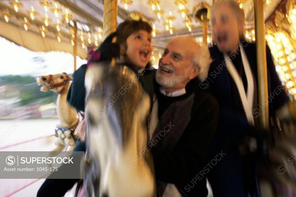 Stock Photo: 1045-175 Granddaughter with her grandparents riding a merry-go-round