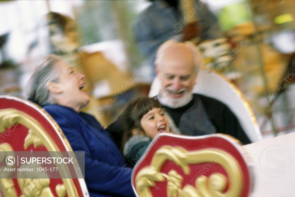 Stock Photo: 1045-177 Granddaughter with her grandparents riding a merry-go-round
