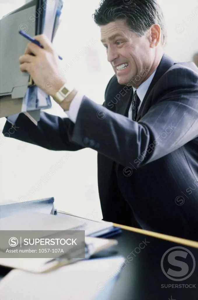 Side profile of a businessman holding documents in anger