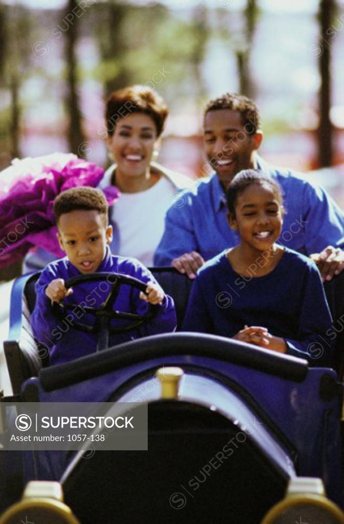 Stock Photo: 1057-138 Parents sitting on an amusement park ride with their son and daughter