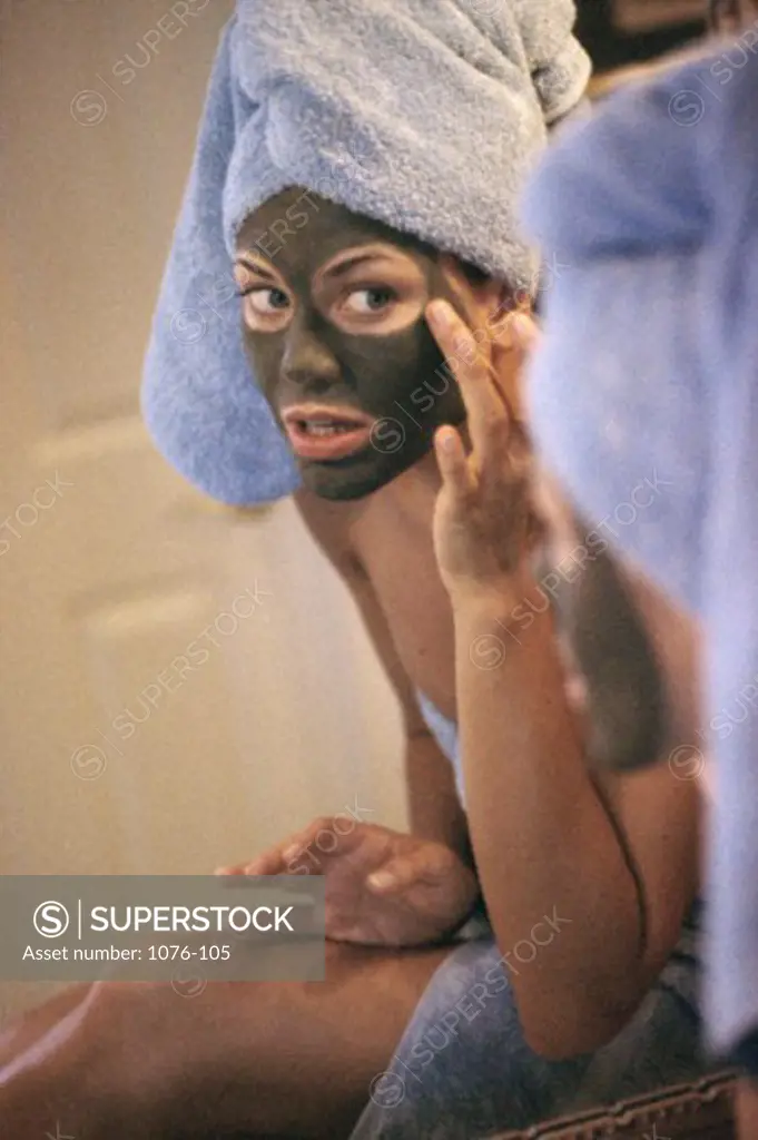 Young woman applying a facial mask