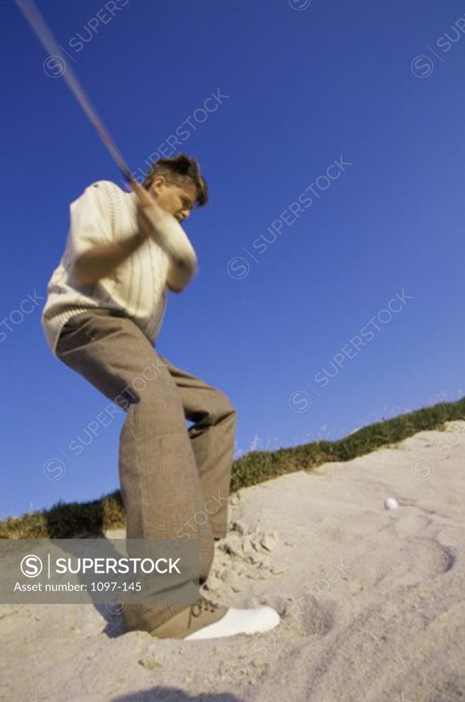 Stock Photo: 1097-145 Low angle view of a mid adult man swinging a golf club