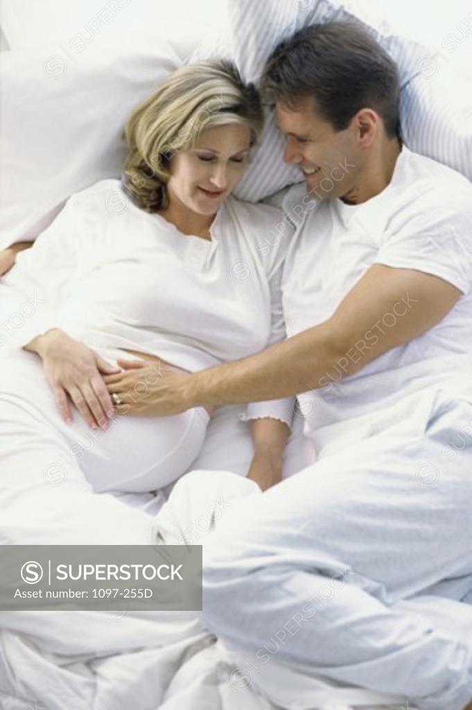 Stock Photo: 1097-255D Husband lying in bed with his pregnant wife