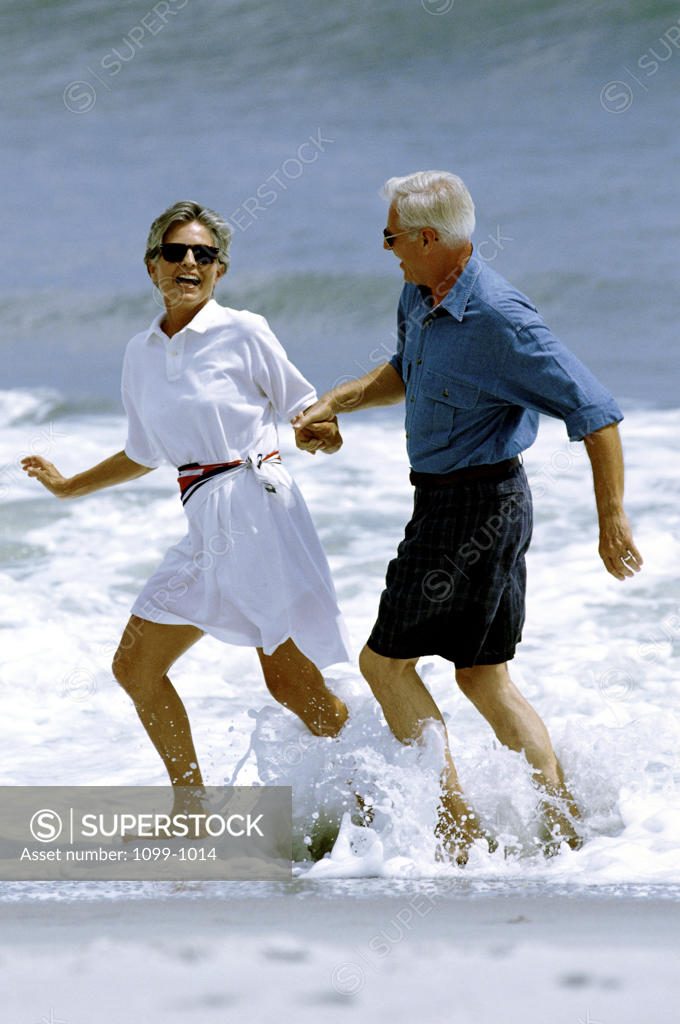 Stock Photo: 1099-1014 Senior couple wading in water on the beach