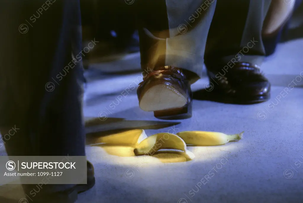 Low section view of a businessman stepping on a banana peel