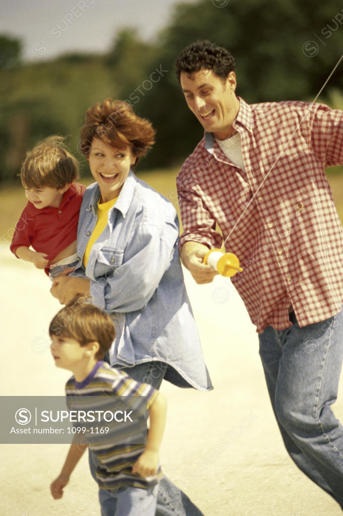 Stock Photo: 1099-1169 Parents flying a kite with their two sons