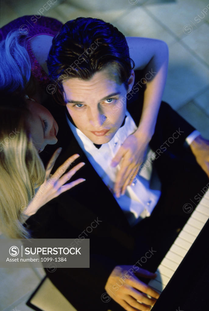 Stock Photo: 1099-1384 Portrait of a young man playing the piano with a young woman hugging him