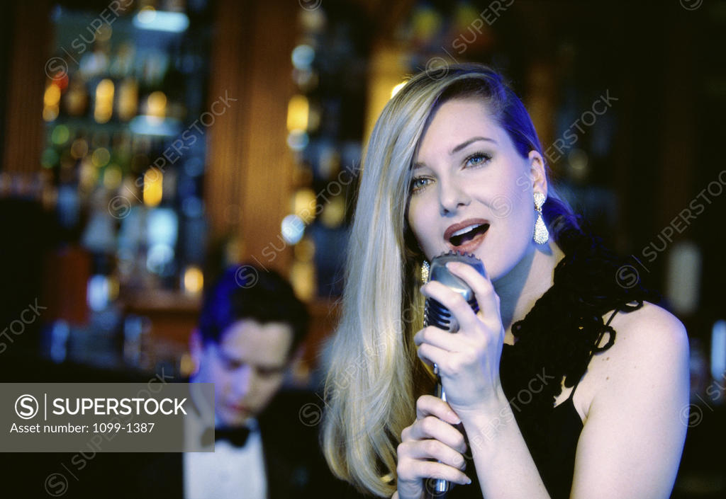 Stock Photo: 1099-1387 Young woman singing into a microphone